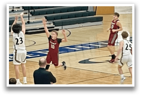 A basketball game is in progress with players on the court. One player is attempting to shoot the ball while another player is trying to block the shot. The basketball is in the air, and the players are focused on the game. AI generated content