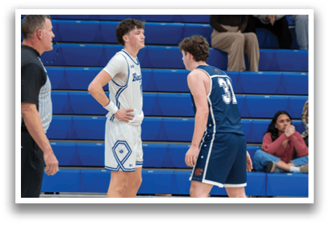 Two basketball players face off on the court, one wearing a white jersey and the other wearing a blue one. The referee stands nearby, watching the game closely. AI generated content
