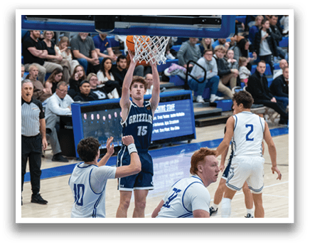 A basketball game is in progress with players on the court. One player is attempting to block a shot, while others are running and playing defense. The crowd is watching the game intently. AI generated content