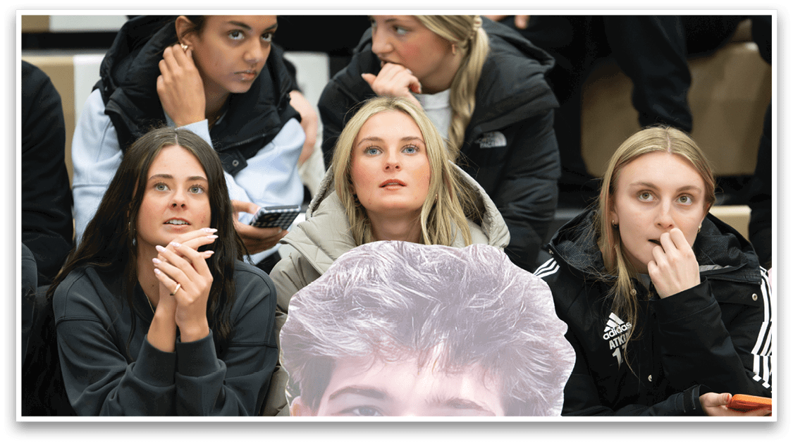A man is sitting in the stands with a cutout of his face on his chest. AI generated content