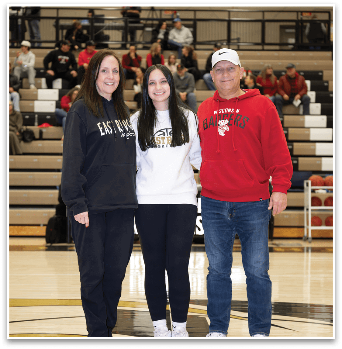 A man, woman, and girl pose for a photo on a basketball court. AI generated content