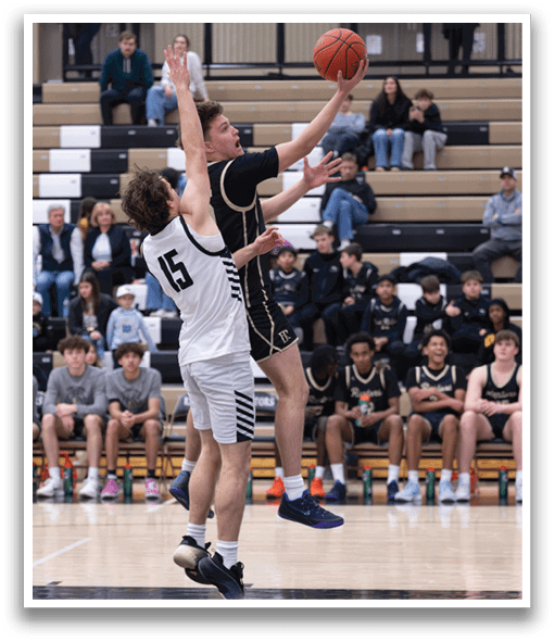 Two basketball players are leaping for the ball, one of them wearing a black shirt. The players are in the air, with the basketball in the air between them. The scene takes place in a gym, with several people watching the game. AI generated content
