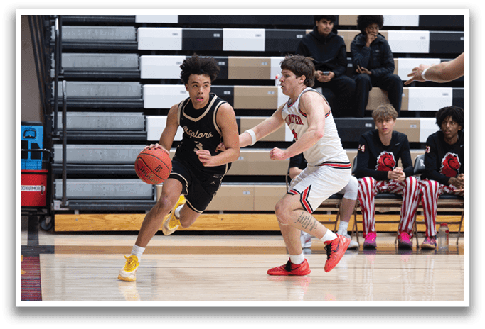 Two basketball players are running for the ball, with one player in a black jersey and the other in a white jersey. A referee is also present, watching the play. The players are wearing sneakers and are in the middle of the court. AI generated content