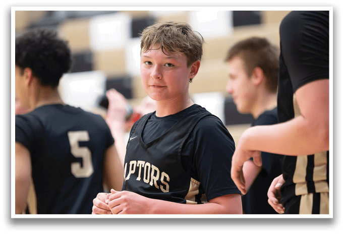 A young boy wearing a basketball uniform stands on a basketball court. AI generated content