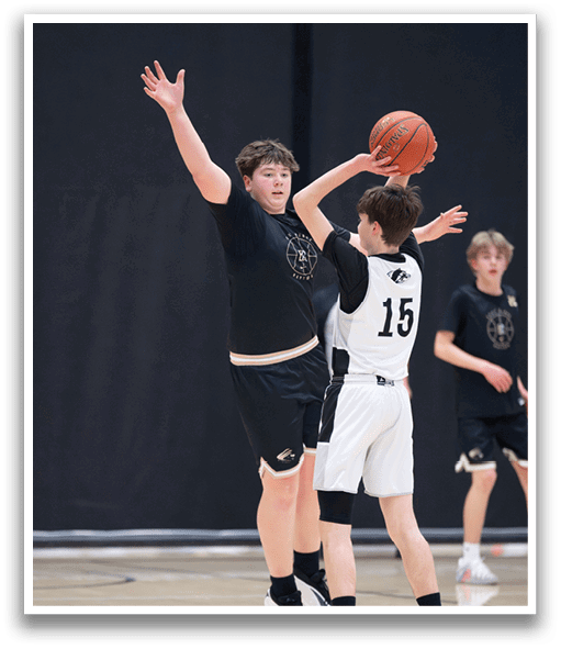 Two young men are playing basketball, one of them is jumping to block a shot. AI generated content