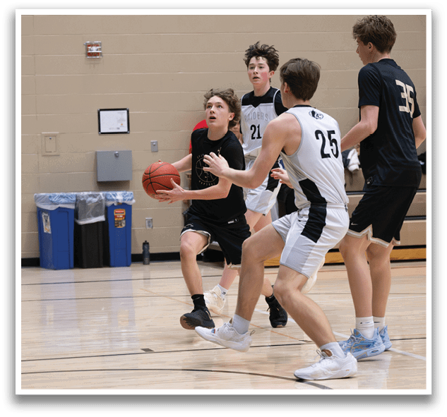A group of young men playing basketball on a court. One player is holding a basketball and another player is trying to block him. AI generated content
