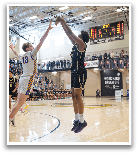 Two basketball players are jumping for the ball, one on the left and one on the right. The player on the left is wearing a white jersey, while the player on the right is wearing a black jersey. The basketball is in the air between them, and there are several other players on the court, watching the action. AI generated content