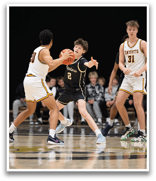 A basketball game is in progress with players on the court. One player is holding a basketball while another player tries to block him. A crowd of people watch the game from the stands. AI generated content