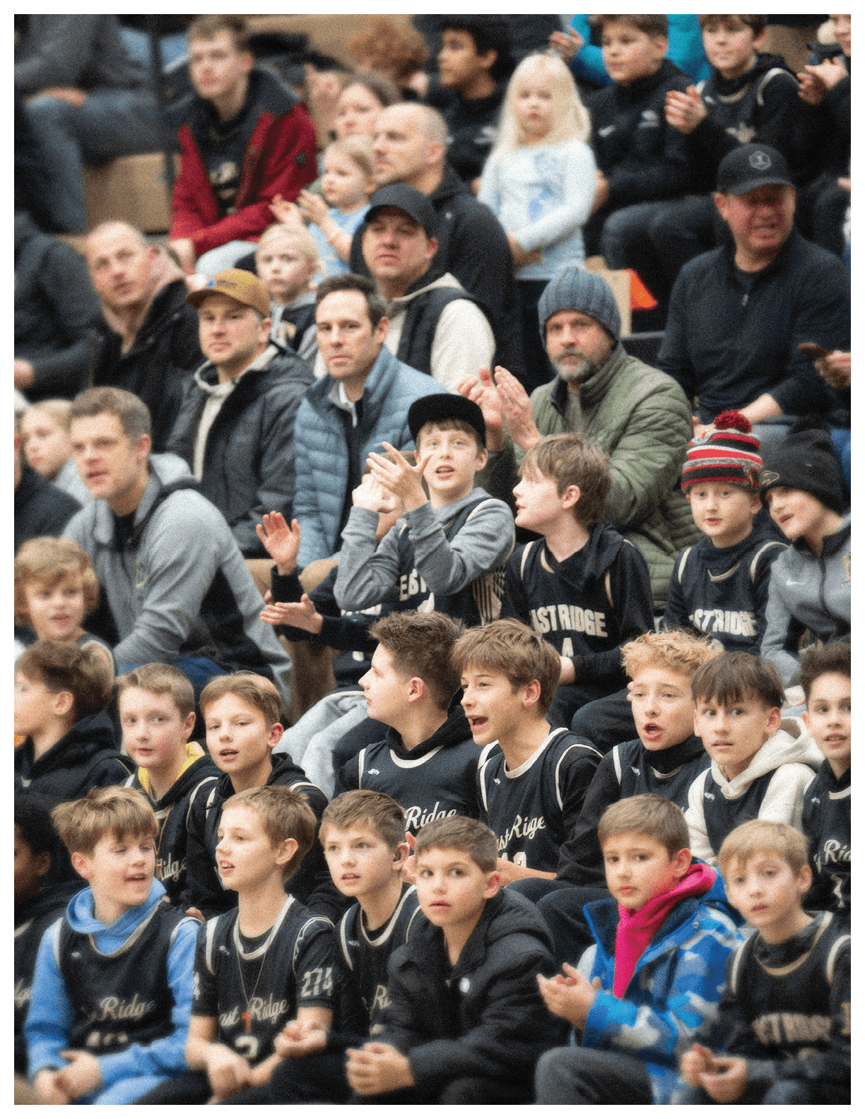 A group of children are sitting in the bleachers, watching a game. They are wearing jerseys and are excited about the event. AI generated content