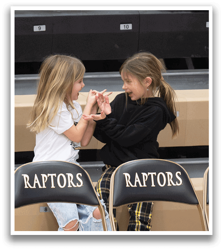 Two young girls are sitting on chairs, one on the left and one on the right. They are both wearing white shirts and are looking at each other. AI generated content