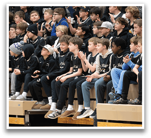 A group of young boys are sitting on a bench, watching a game. AI generated content