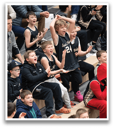 A group of young boys are sitting on a bench, watching a game. They are wearing basketball jerseys and are excited about the event. AI generated content
