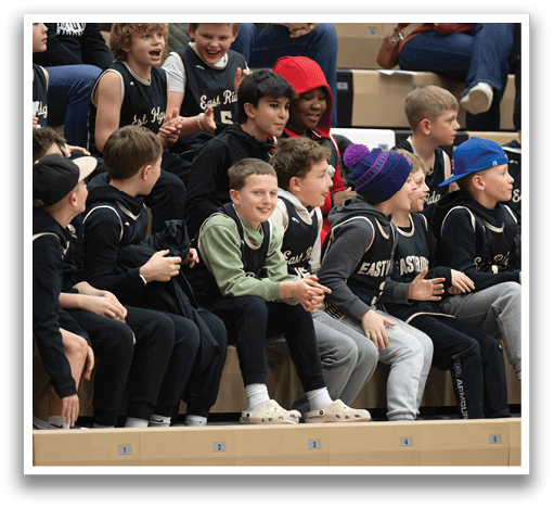 A group of young boys wearing basketball uniforms are sitting on a bench. AI generated content
