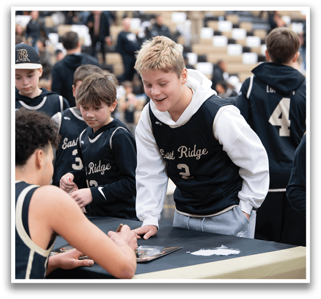 A group of young people are gathered around a table, with one of them signing autographs for the others. AI generated content
