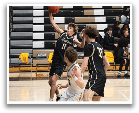 A basketball game is in progress with players on the court. One player is attempting to shoot the ball while another player tries to block the shot. The basketball is in the air, and the players are focused on the game. AI generated content