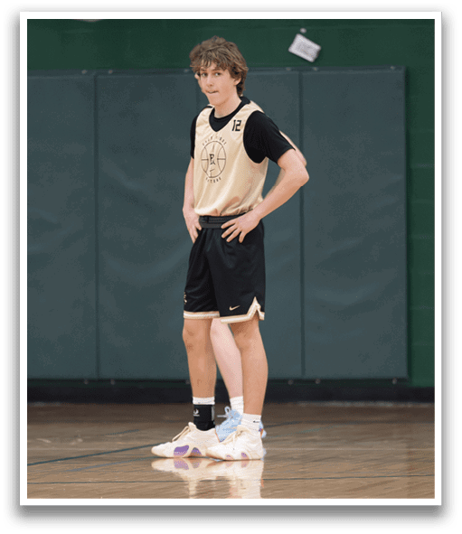 A man wearing a black and gold shirt stands on a basketball court. AI generated content