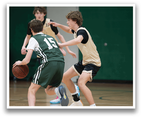 Two boys are playing basketball, one wearing a green jersey and the other wearing a gold jersey. They are both running for the basketball, which is located in the middle of the court. AI generated content