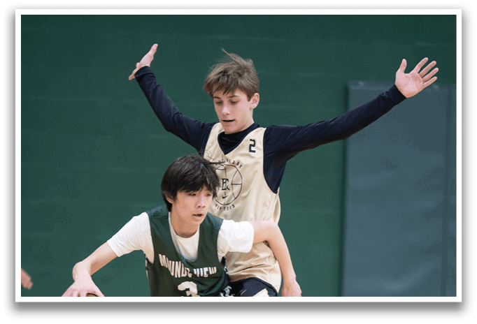 Two boys playing basketball, one wearing a green jersey and the other wearing a gold jersey. AI generated content