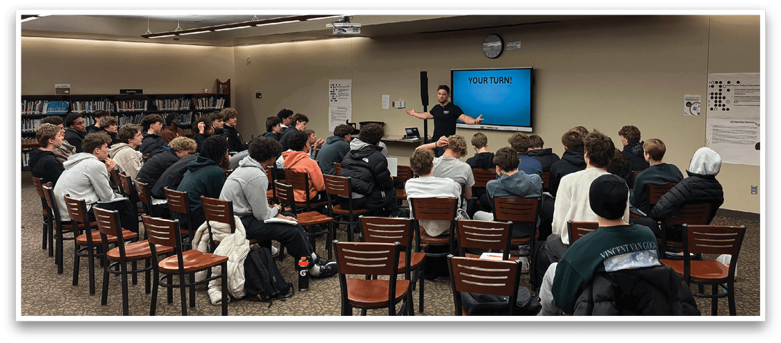 A group of people are sitting in a circle in a classroom, listening to a man who is standing in front of them. AI generated content