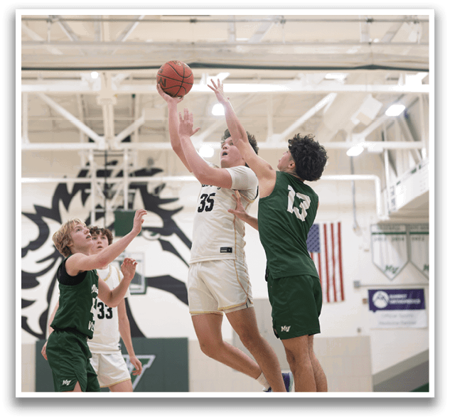 A basketball game is in progress with players on the court. One player is jumping to block a shot, while another player is trying to get the ball. The players are wearing uniforms and are actively engaged in the game. AI generated content