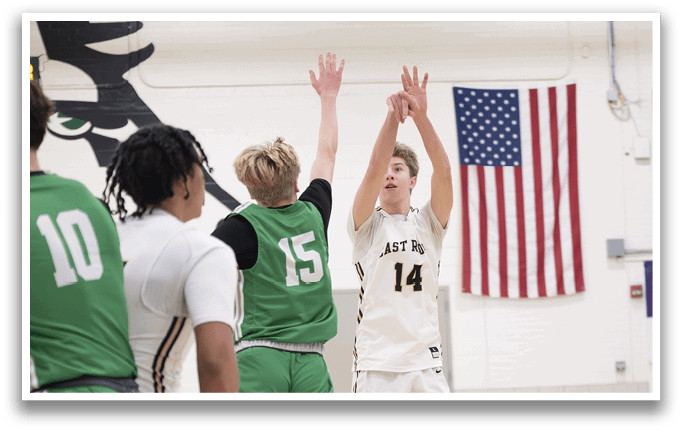 A basketball game is in progress with players on the court. A man is jumping up to shoot the ball, while another player is trying to block his shot. The scene also features a flag hanging on the wall. AI generated content