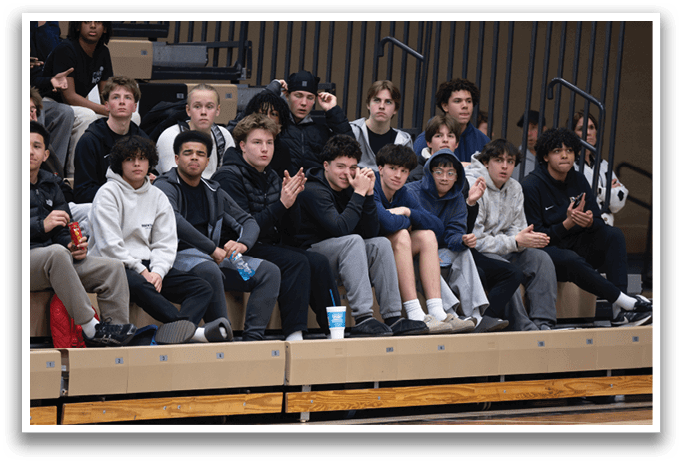 A group of people are sitting on a bench, watching a game. AI generated content