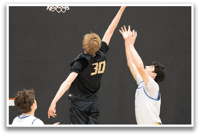 Three basketball players are playing in a game. One player is jumping up to block a shot, while the other two players are trying to get the ball. The players are wearing uniforms and are in the middle of the action. AI generated content