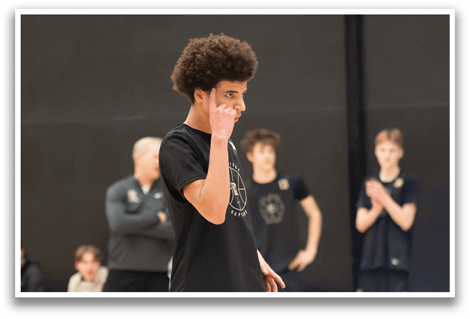 A man in a black shirt and black shorts is walking on a basketball court. AI generated content