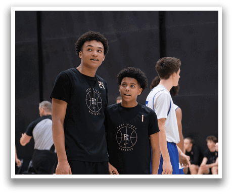 Two young men wearing basketball uniforms stand on a basketball court. AI generated content