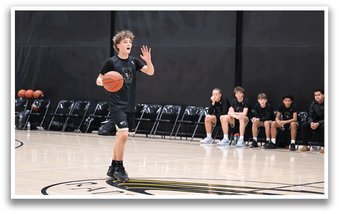 A boy is holding a basketball in a gym, surrounded by other boys. AI generated content
