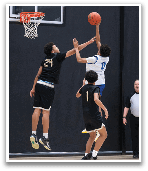 Two basketball players are jumping for the ball, with one player wearing a black jersey and the other wearing a white jersey. The players are both reaching for the basketball, which is in the air. A referee is also present in the scene, watching the play unfold. AI generated content