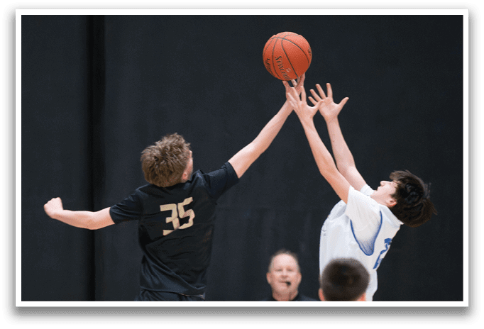 Two basketball players jump in the air to reach for the ball. AI generated content