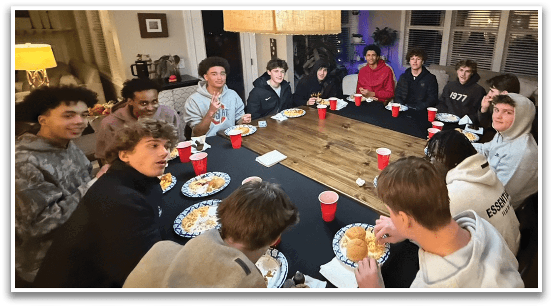 A group of people are sitting around a table in a room, eating and drinking from cups and plates. AI generated content