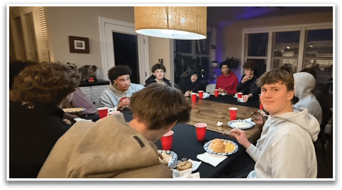 A group of people are sitting around a table with cups and plates of food. AI generated content