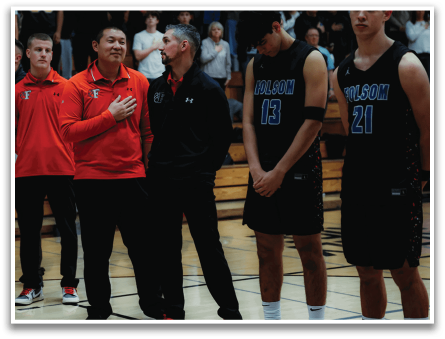 A group of men stand on a basketball court, some wearing orange shirts and others wearing blue. They are lined up, possibly for a game or a ceremony. AI generated content