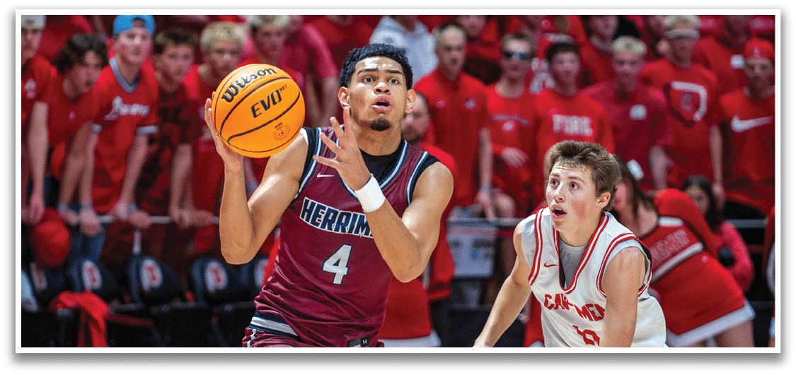 A basketball player in a maroon uniform is holding a basketball and running down the court. A boy in a red uniform is running towards him, trying to block his shot. AI generated content