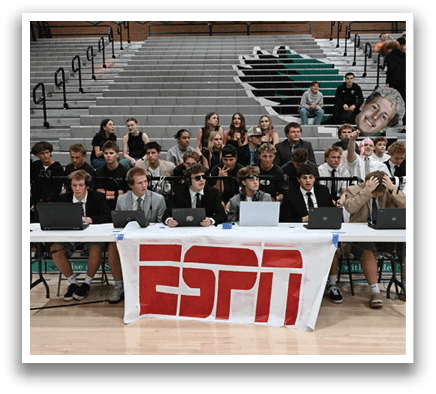 A group of people are sitting in chairs in front of a large banner that says “ESPN." They are wearing suits and ties, and some of them are using laptops. AI generated content