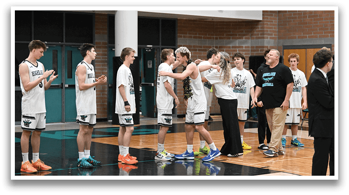 A group of young men and women are standing on a basketball court, some of them wearing white shirts. They are holding hands and hugging each other, with some of them also holding up their shirts. The scene appears to be a celebration or a commemorative moment for the group. AI generated content
