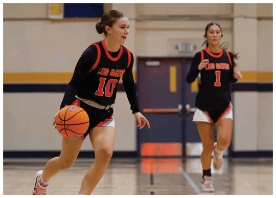 Two girls playing basketball, one with the ball and the other running. AI generated content