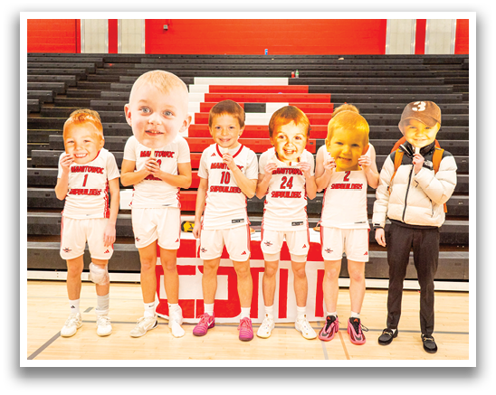 A group of people are standing on a basketball court, each holding a cutout of a baby's face. AI generated content