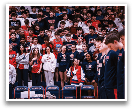 A group of people are standing on a basketball court, with some of them wearing red and white uniforms. They are all facing the same direction, possibly watching a game or listening to a speaker. The crowd is composed of both men and women, and they are all standing close to each other. AI generated content