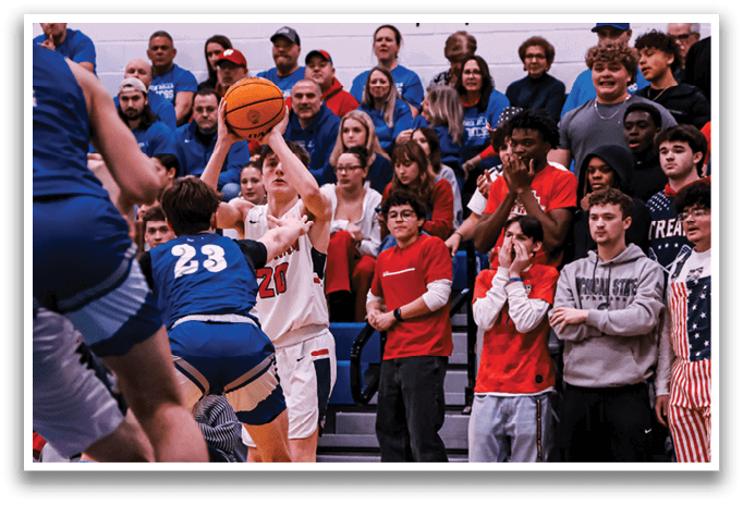 A basketball game is taking place with a crowd of people watching. A player is in the process of shooting the ball. AI generated content