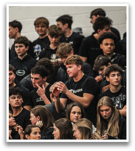 A group of people are sitting in the bleachers, watching a game. They are wearing black shirts and are engaged in the event. AI generated content