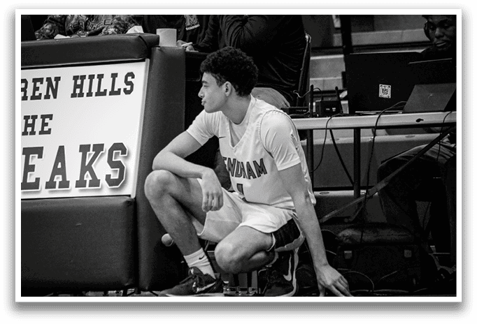 A man sits on the floor of a basketball court, wearing a white shirt and shorts. AI generated content