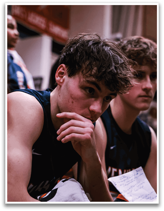 A group of young men are sitting on a bench, with one of them looking down at his hands. They are all wearing uniforms, suggesting they are part of a team. AI generated content