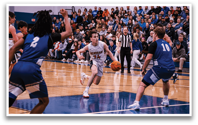 A basketball game is taking place with a group of people on the court. One player is holding the ball, while another player is trying to block him. There are several other players on the court, some of whom are wearing blue and white uniforms. The audience is watching the game intently, with some people sitting on chairs and others standing. AI generated content