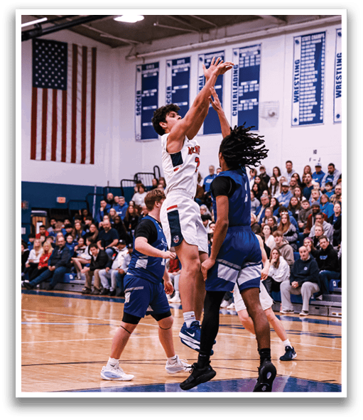 A basketball game is taking place with two teams playing against each other. One player is attempting to block a shot by another player who is trying to score. The crowd is watching the game intently. AI generated content