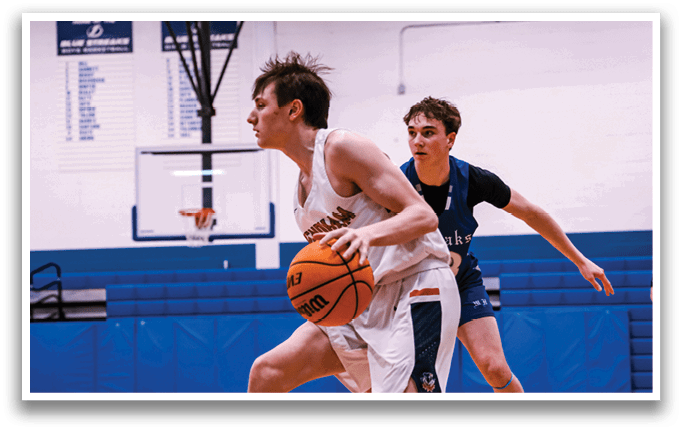 Two young men playing basketball on a court. One man is holding a basketball while the other is running towards him. AI generated content