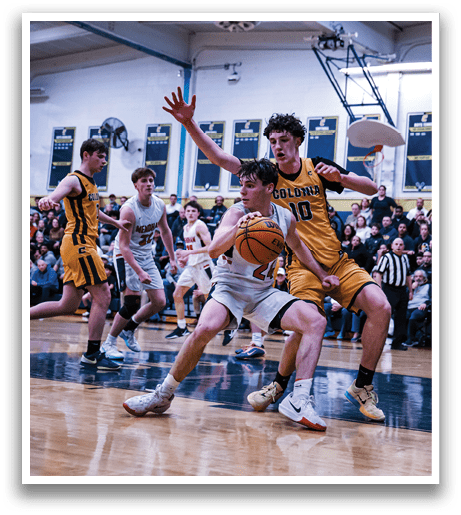 A basketball game is in progress with players on the court. A man in a yellow shirt is trying to block a shot by another player. The crowd watches intently as the players compete. AI generated content