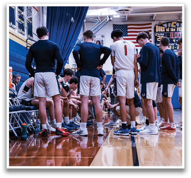A group of young men are standing on a basketball court, wearing uniforms and holding their hands on their hips. They are gathered around the court, possibly discussing their game strategy or taking a break. AI generated content